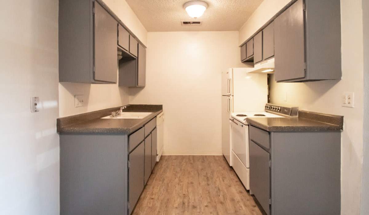 Modern kitchen with gray cabinets, stainless steel appliances, and wood-style flooring at Riatta Ranch Apartments in Abilene, Texas