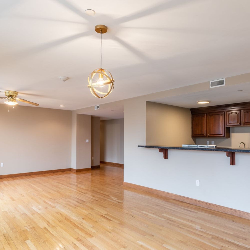 Spacious apartment living area with open kitchen and hardwood floors at Stratford House in Dayton, Ohio