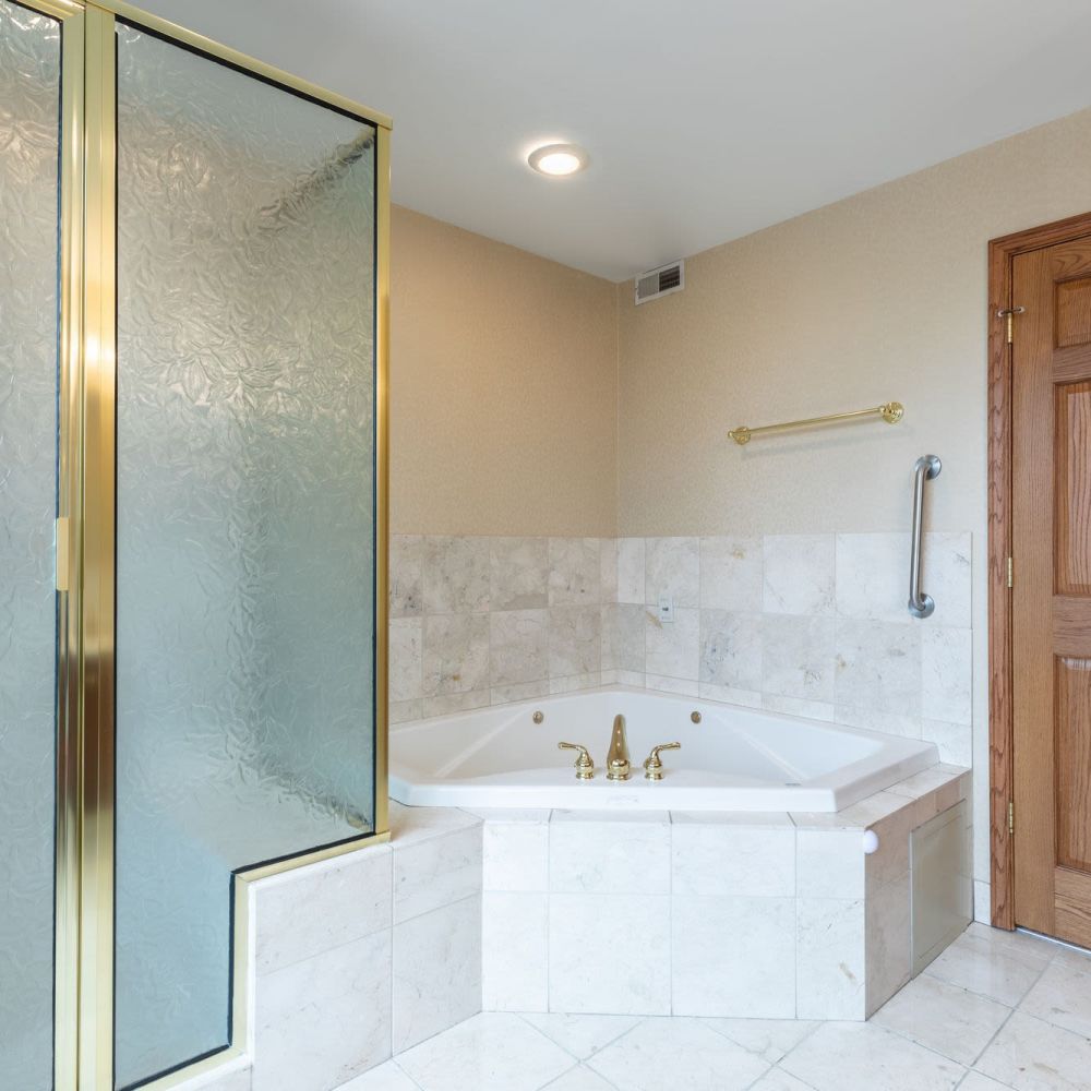 Bathroom with glass shower enclosure and corner bathtub at Stratford House in Dayton, Ohio