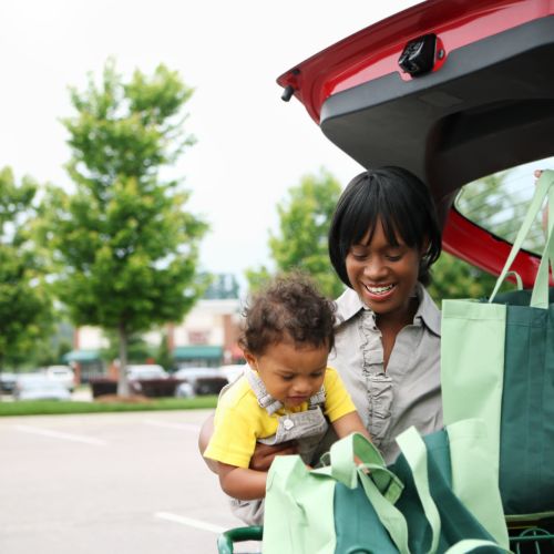 Woman unloading groceries with toddler at car Balcones Trails in Kyle, Texas