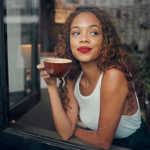 Woman enjoying coffee by window at Jefferson Manor Townhomes in Fairport, New York