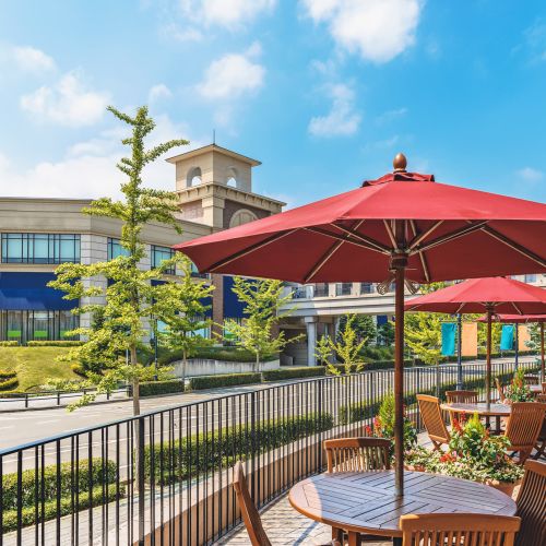 Outdoor dining area with umbrellas and greenery at Jefferson Manor Townhomes in Fairport, New York