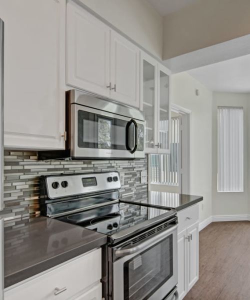 Kitchen with white cabinets, tile backsplash, and stainless steel appliances at Dryden in Phoenix, Arizona
