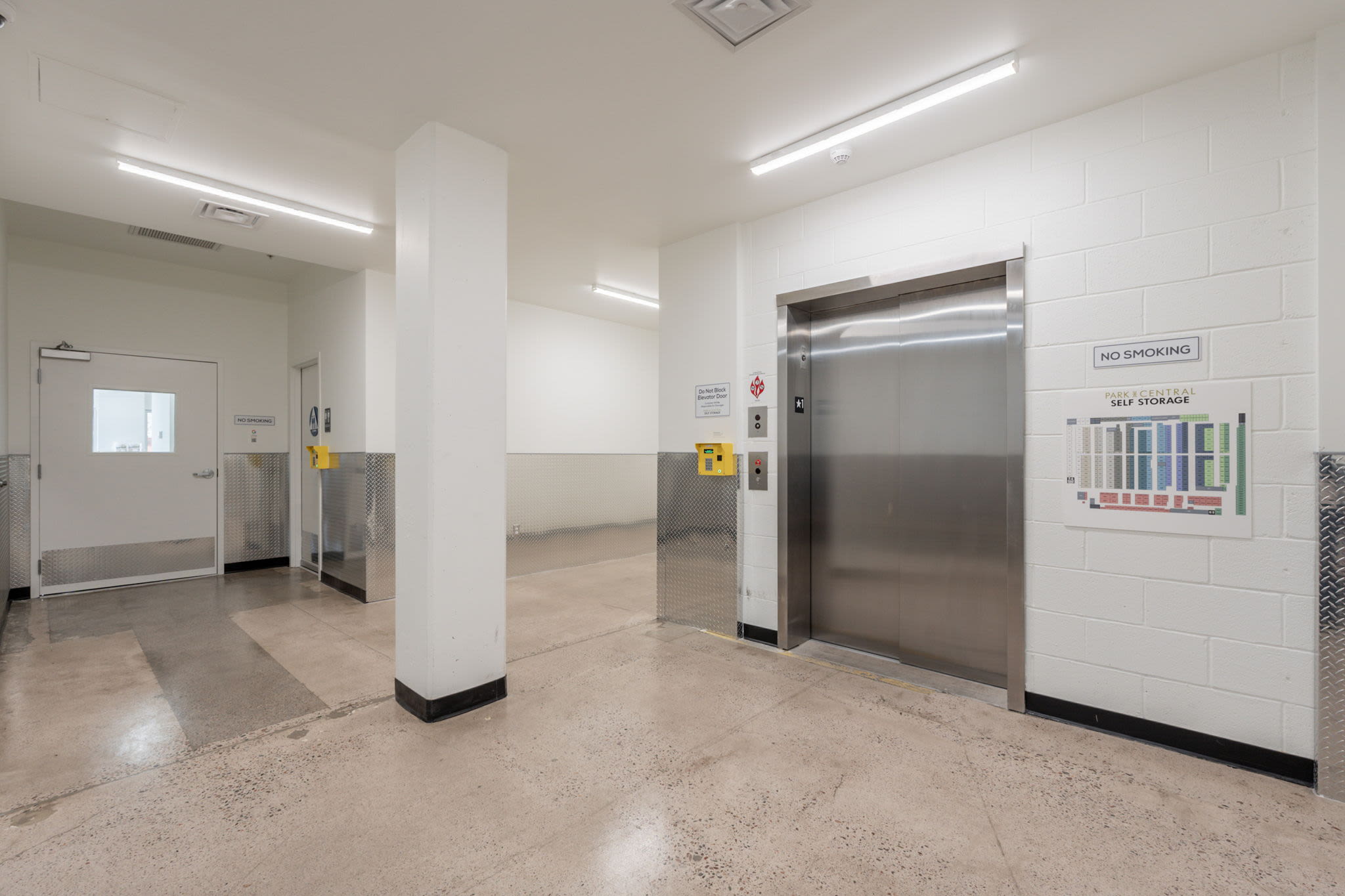 Hallway with elevator, two doors, and a 'No Smoking' sign near a storage map at Park Central Self Storage in Phoenix, Arizona