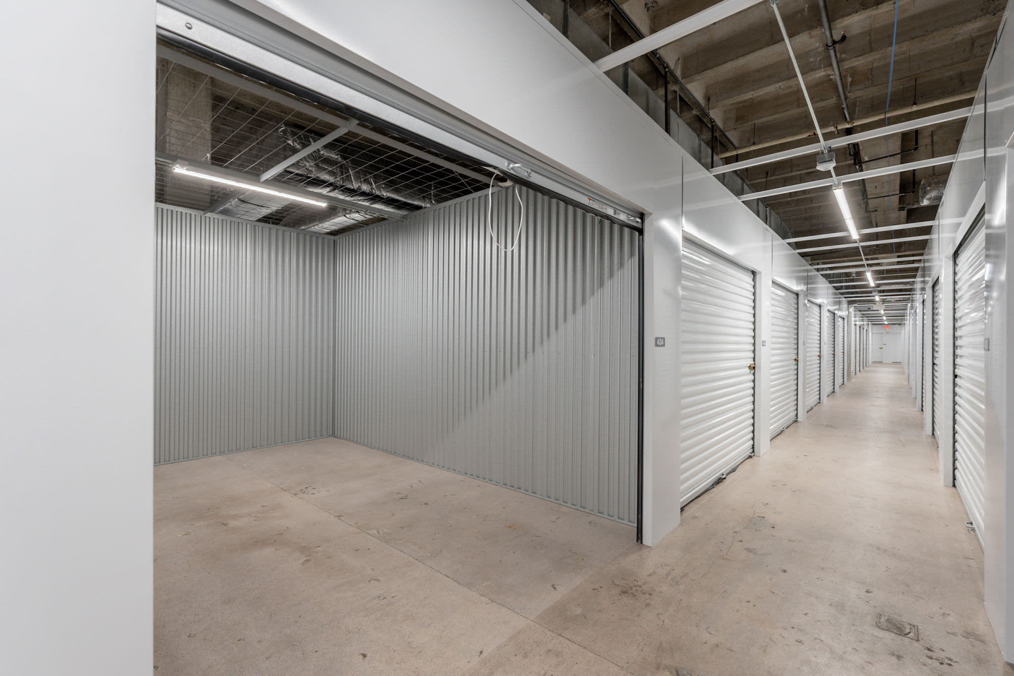 Storage hallway with one open unit showing an empty interior at Park Central Self Storage in Phoenix, Arizona