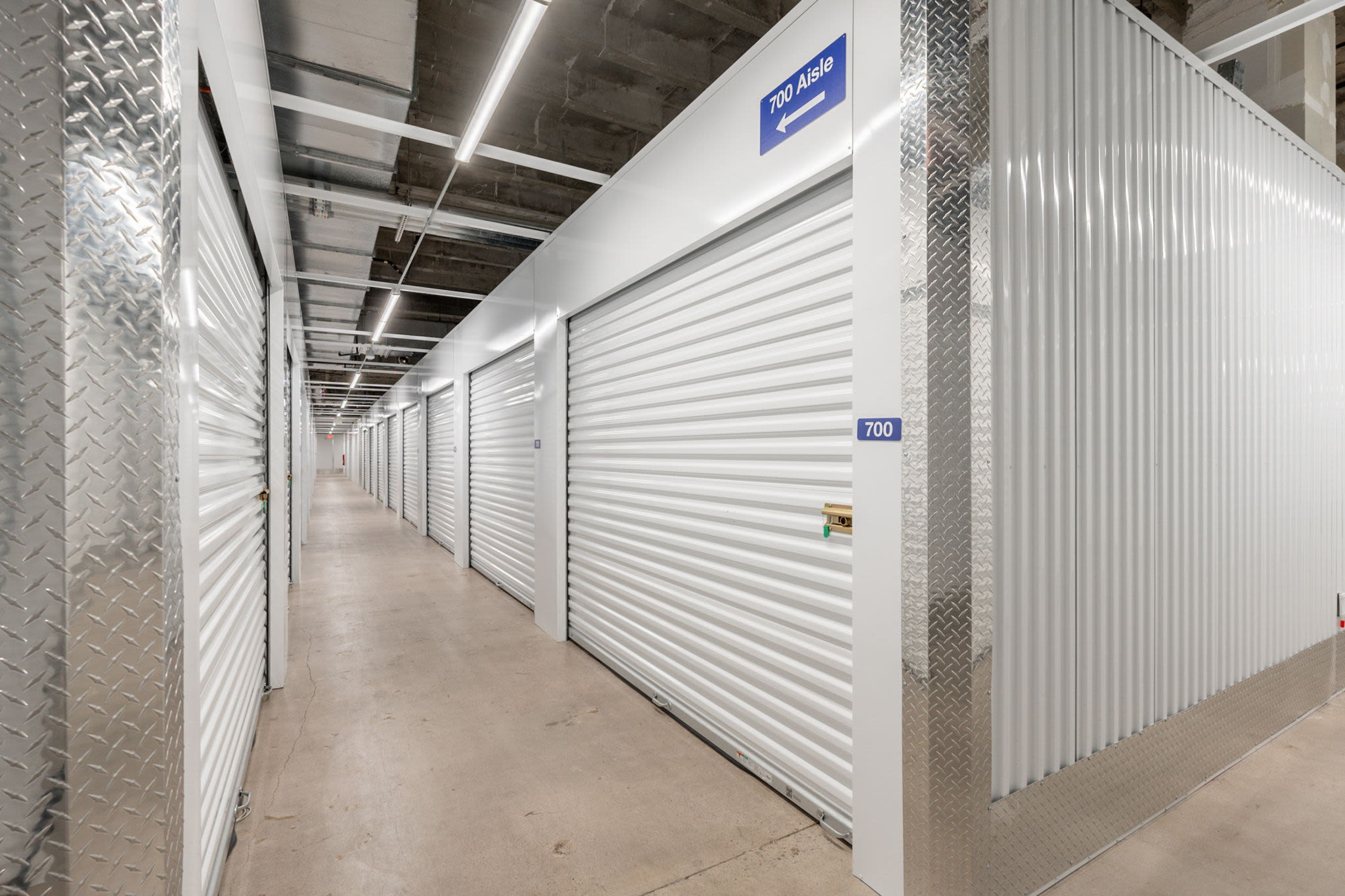 Storage facility hallway with white roll-up doors at Park Central Self Storage in Phoenix, Arizona