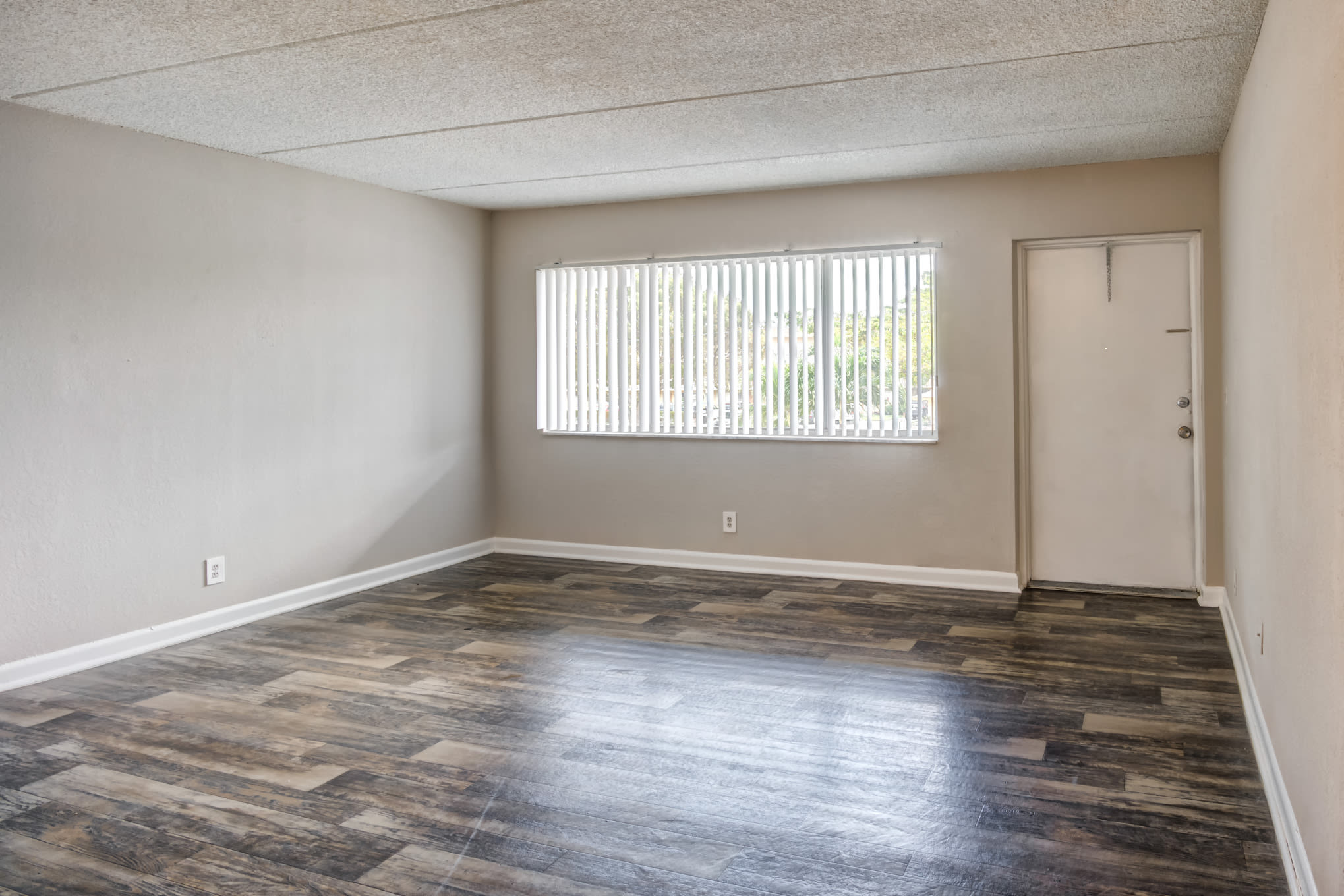 Front door and living room with wood-style flooring at Coronado Springs in Palm Springs, Florida