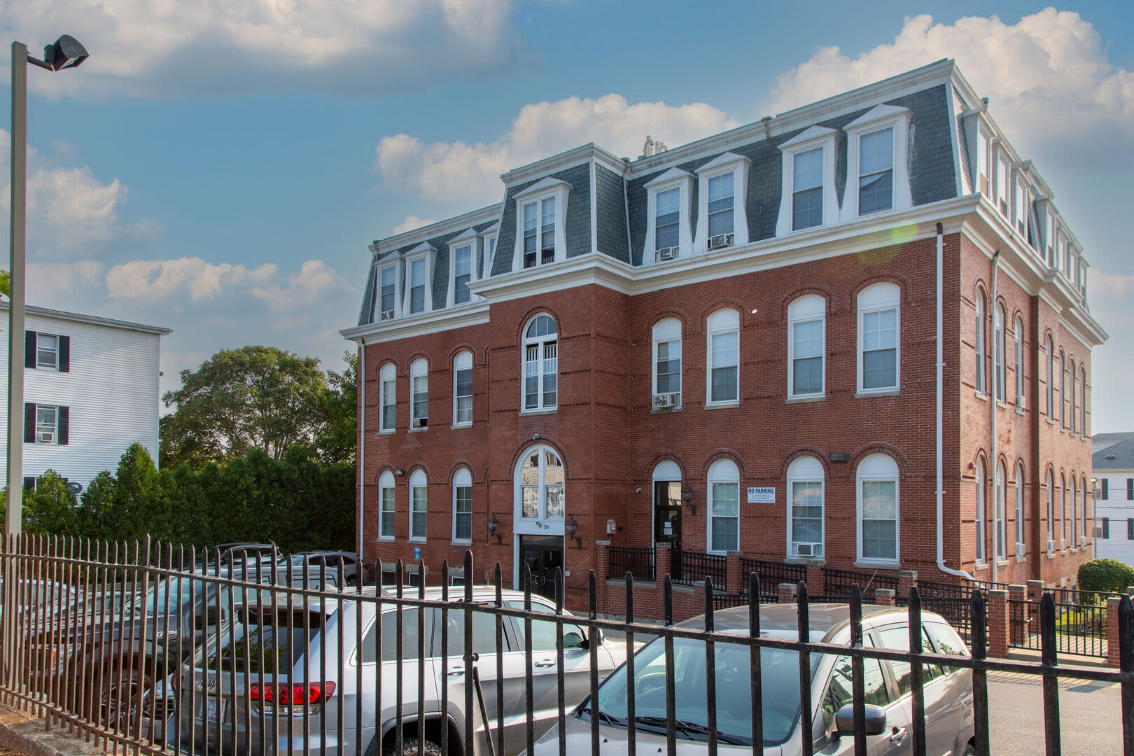 Exterior image of the building with community parking area at the front at Acushnet Commons in New Bedford,Massachusetts