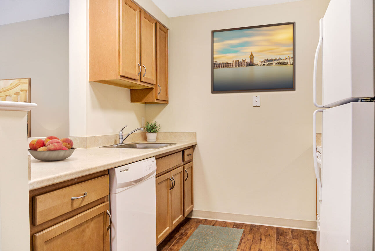 Kitchen with dishwasher, wooden cabinets and vinyl plank flooring at Barstow Village in Hanover, Massachusetts