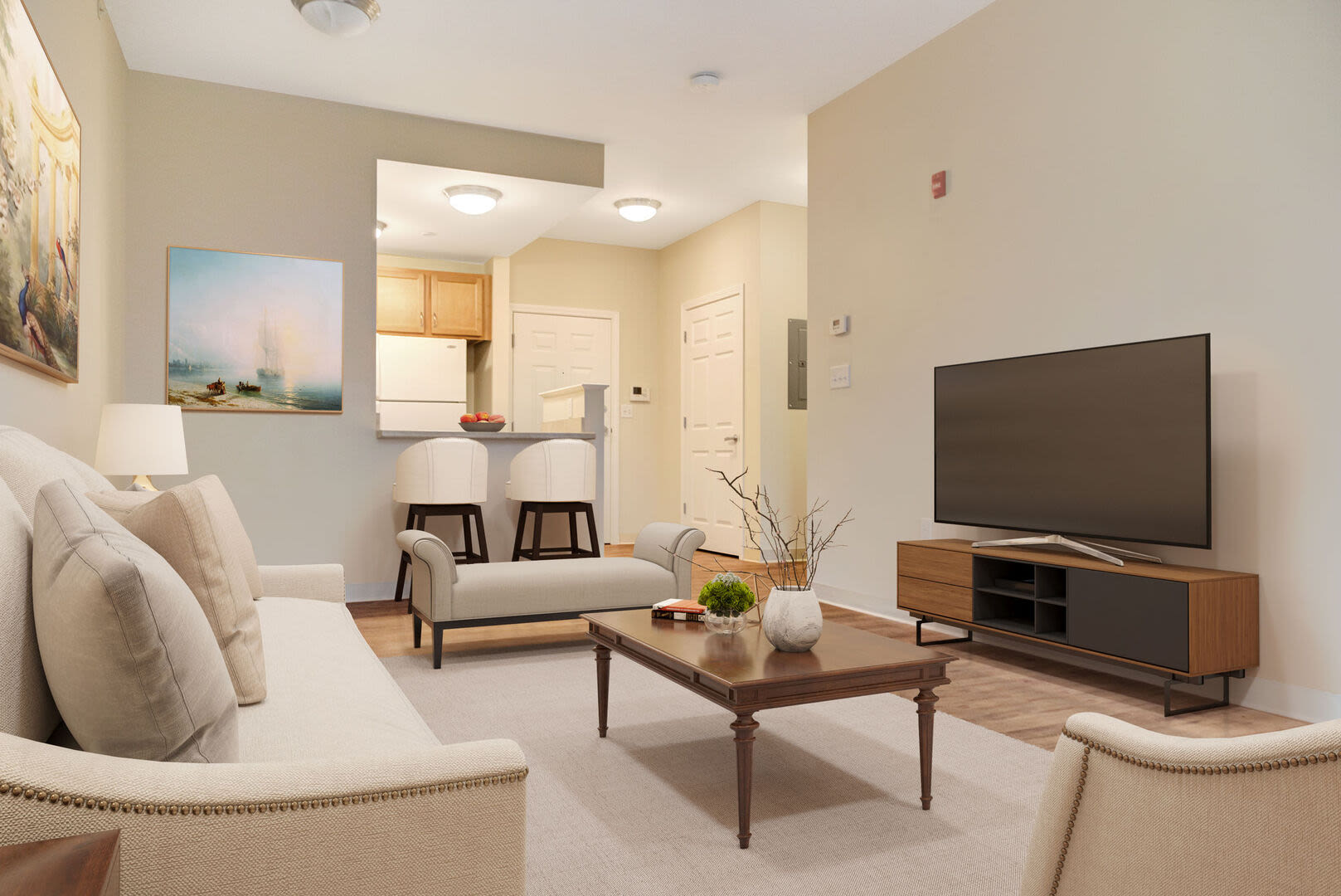Living room with TV, coffee table, couch and close access to kitchen with island at Barstow Village in Hanover, Massachusetts
