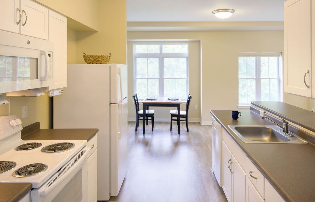 Modern kitchen with white appliances at Bedford Green Apartments in Bedford, Massachusetts