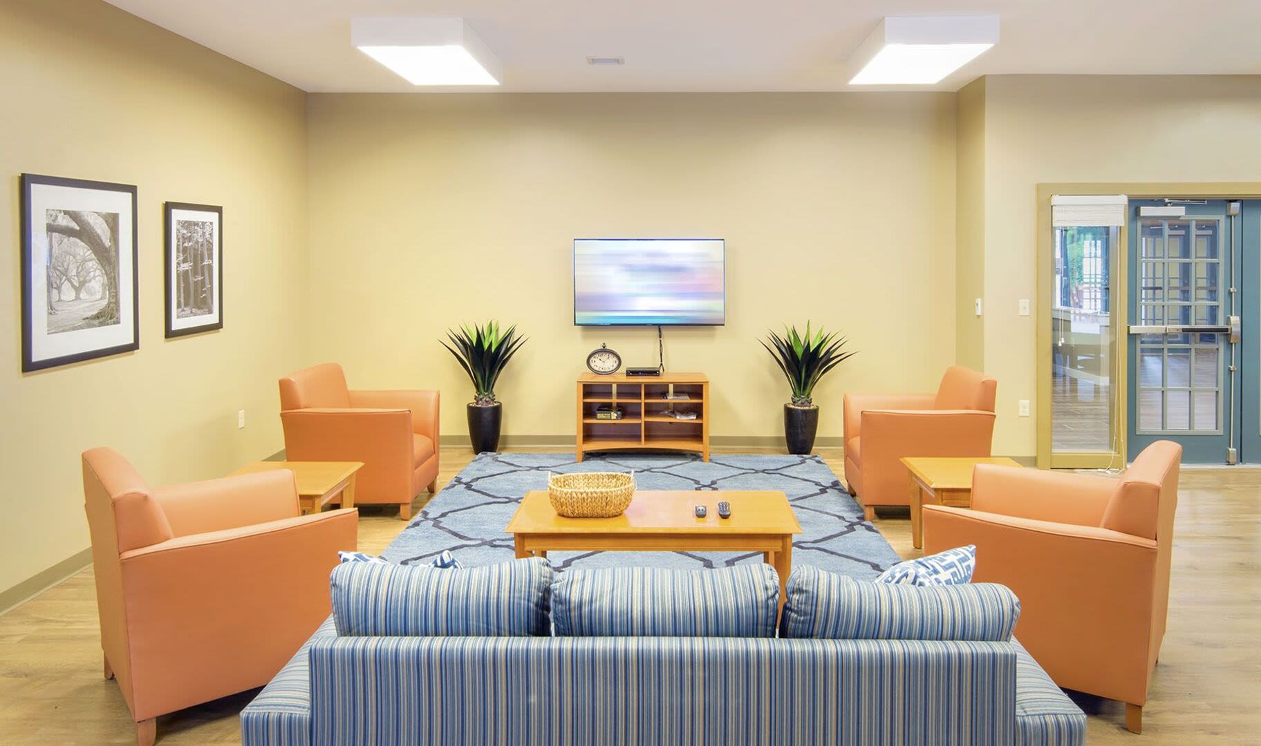 Community clubhouse with couch, chair and flat screen television at Bedford Green Apartments in Bedford, Massachusetts