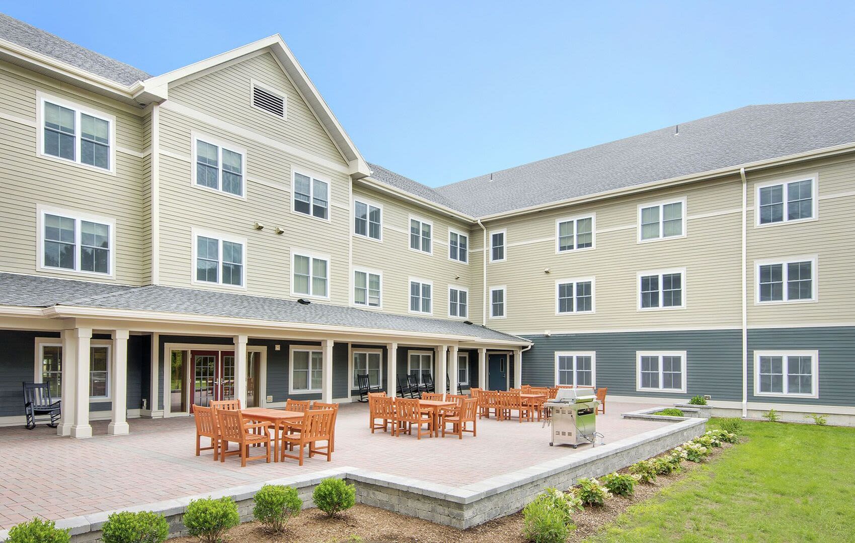 Community outdoor seating area with grill at Bedford Green Apartments in Bedford, Massachusetts