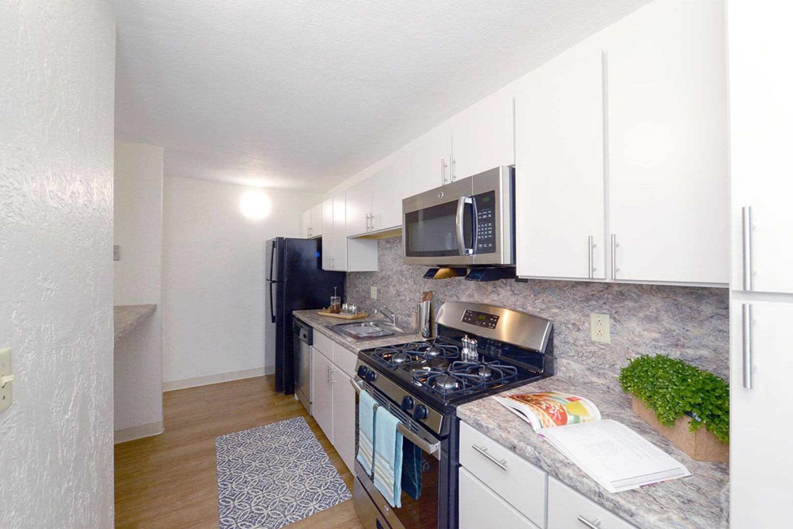 Modern kitchen with sleek granite countertops and a refrigerator at Braintree Village in Braintree, Massachusetts