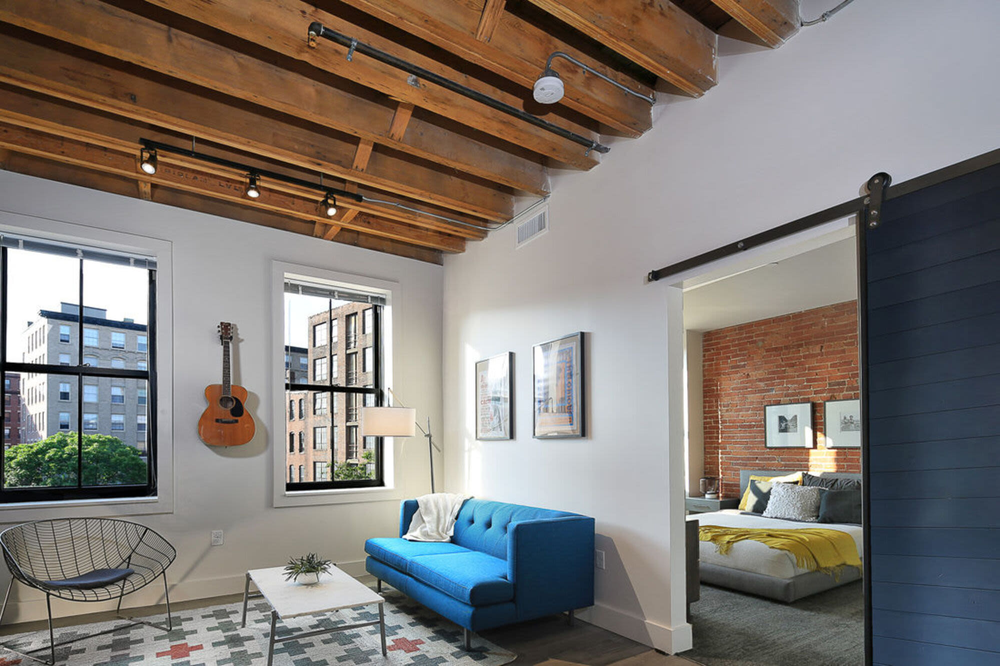 Living room with couch, coffee table, guitar and windows at J.M. Lofts in Haverhill, Massachusetts