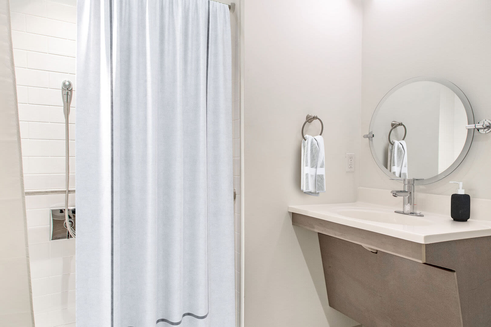 Bright bathroom with vanity lights, sink and shower at Mercantile Wharf in Boston, Massachusetts
