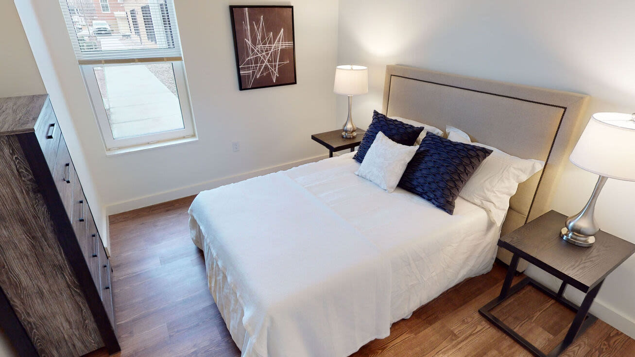Bedroom with a bed window and a night stand with a lamp at The Mcelwain School Apartments in Bridgewater,Massachusetts