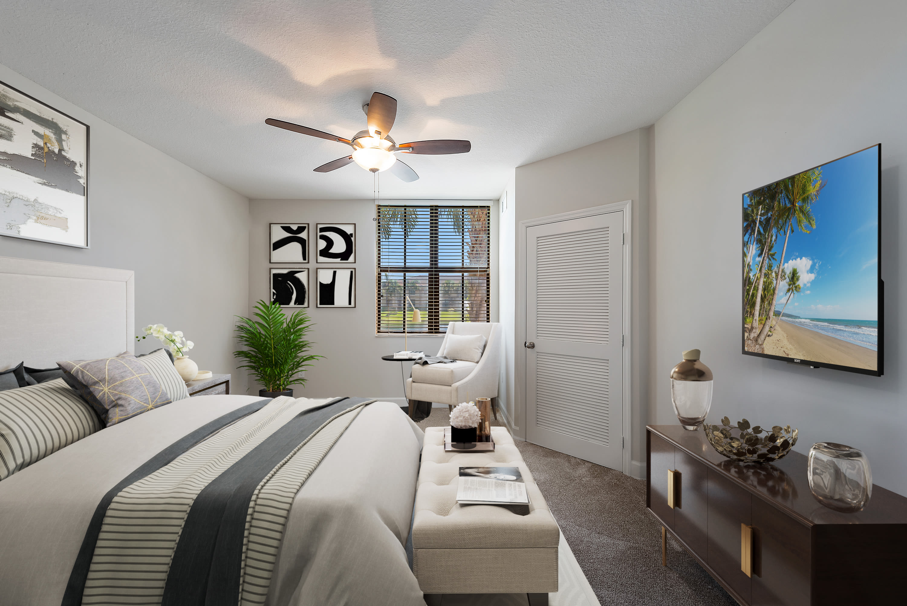 Well-lit, carpeted model bedroom with walk-in closet and a ceiling fan at The Residences at Lakehouse in Miami Lakes, Florida