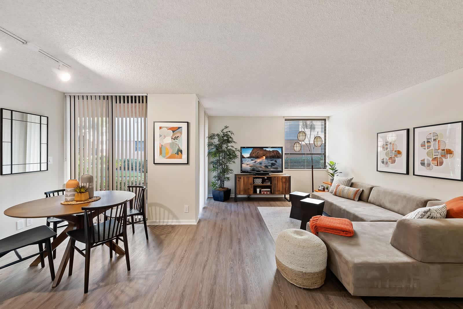 Model living room and dining room with private balcony access at New Barn Apartments in Miami Lakes, Florida