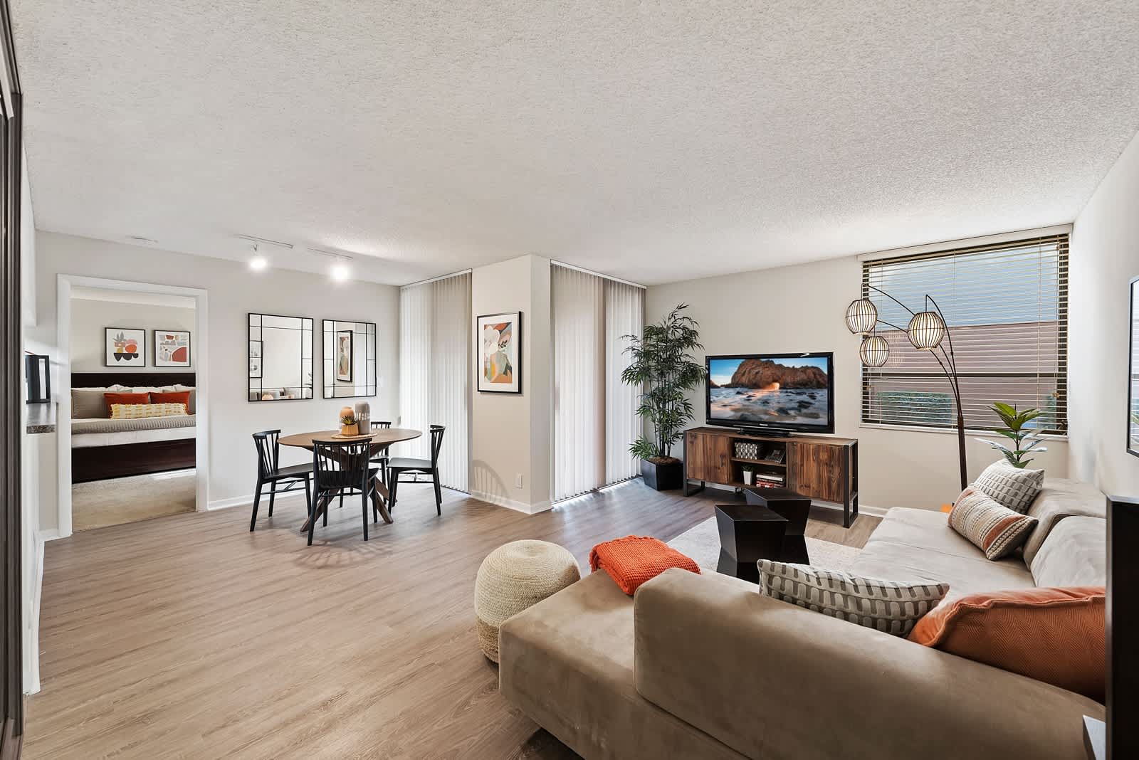 Model dining and living area with wood-style flooring and sliding door access to a private patio at New Barn Apartments in Miami Lakes, Florida