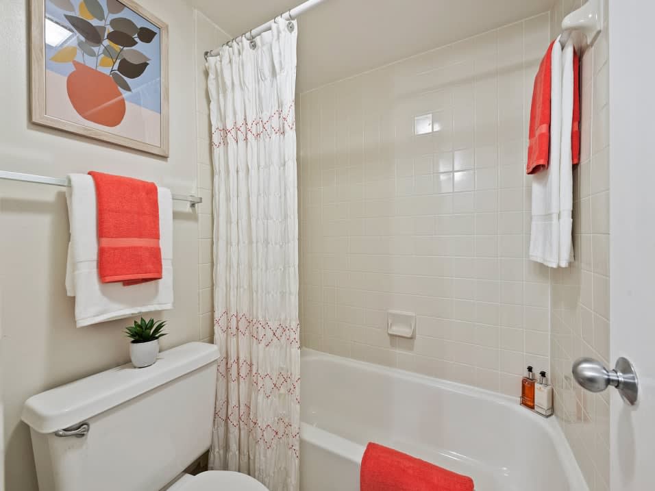 Model bathroom with shower and bath combination at New Barn Apartments in Miami Lakes, Florida