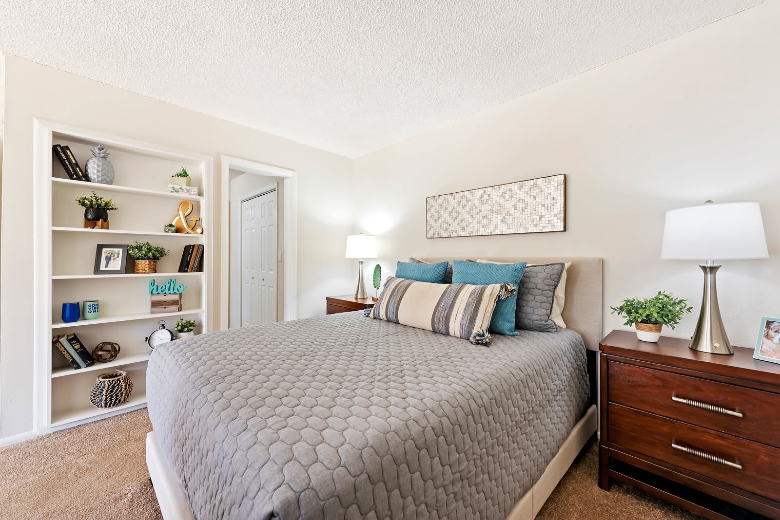 Model bedroom with walk-in closet and a built-in bookshelf at Executive Apartments in Miami Lakes, Florida