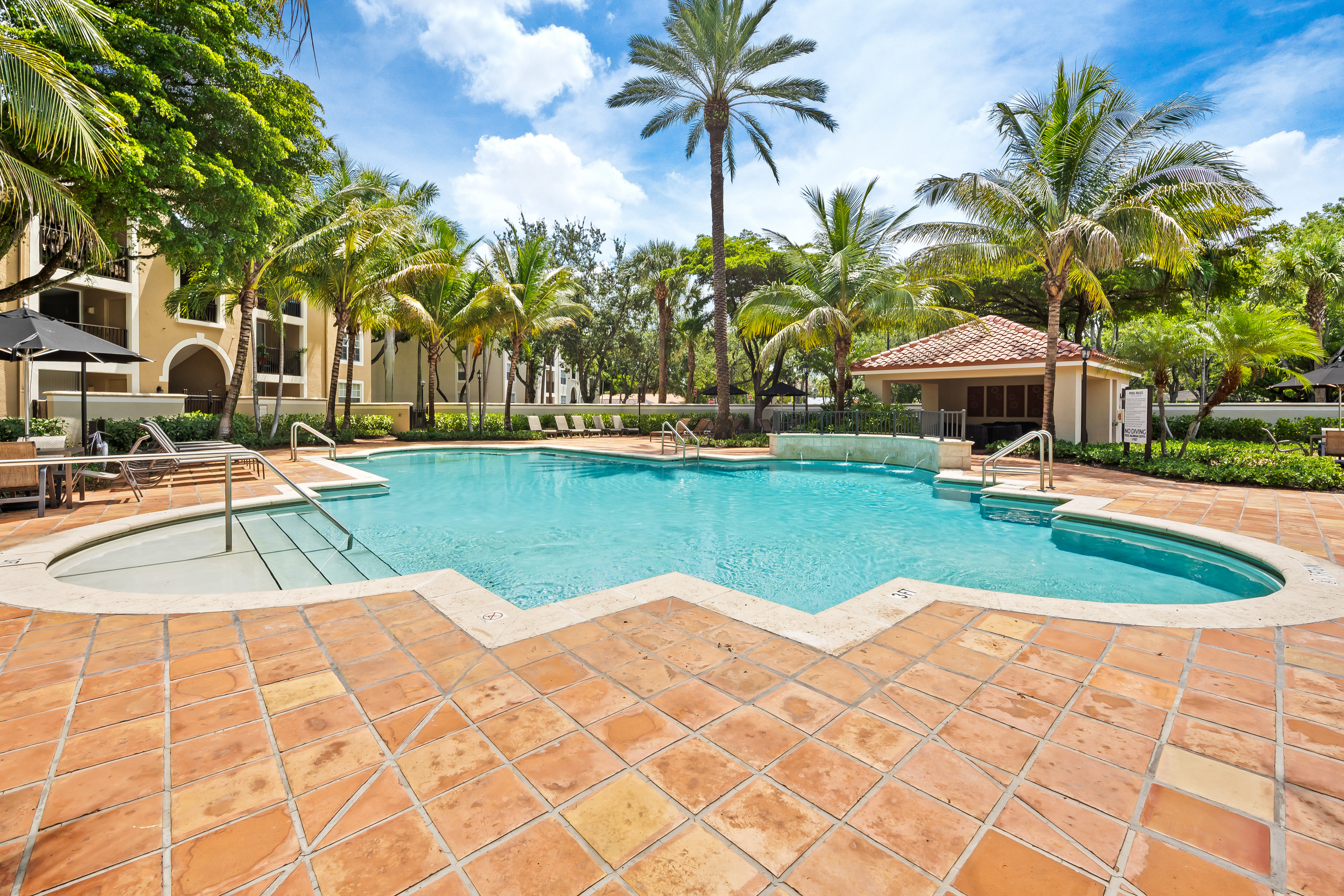 Resort-style swimming pool with Spanish tile deck at Crescent House Apartments in Miami Lakes, Florida