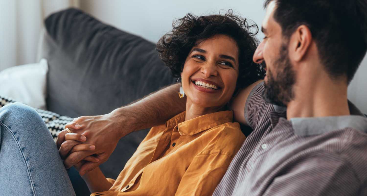 Couple sharing a laugh on the couch in their apartment at Cypress Point Apartments in Shawnee, Oklahoma