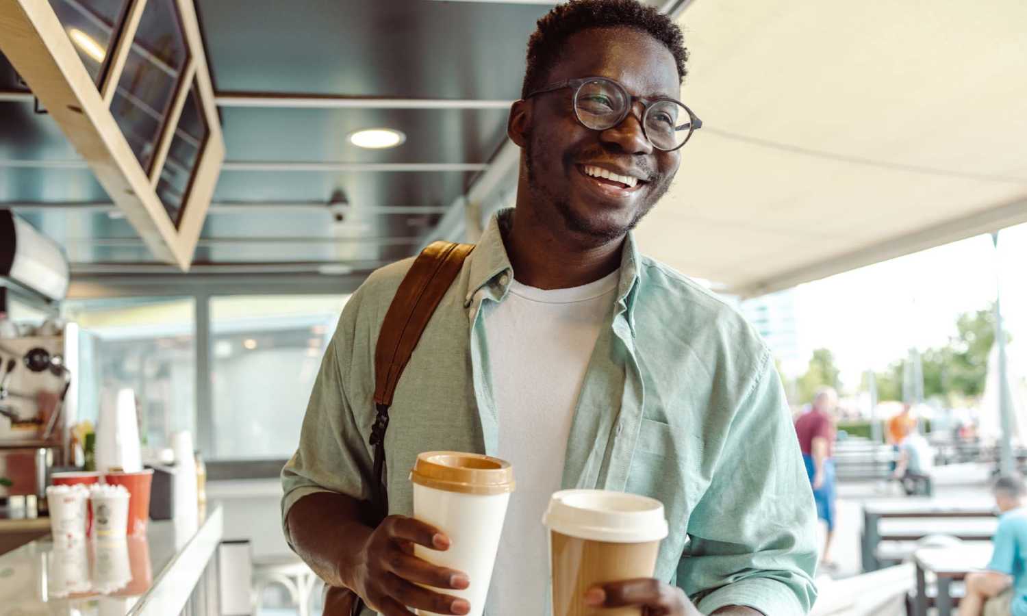Smiling man holding two coffee cups in a casual café setting at The Carlton of West Melbourne in West Melbourne, Florida 
