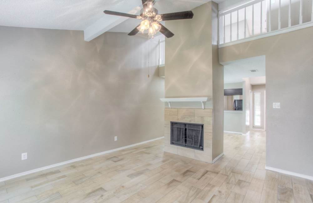 Spacious and well-lit apartment living area with fireplace and lighted ceiling fan at The Quorum At Trophy Club in Trophy Club, Texas