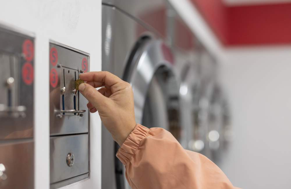 A resident trying to use washing machine in the community laundry room at Douglas Park in Compton, California