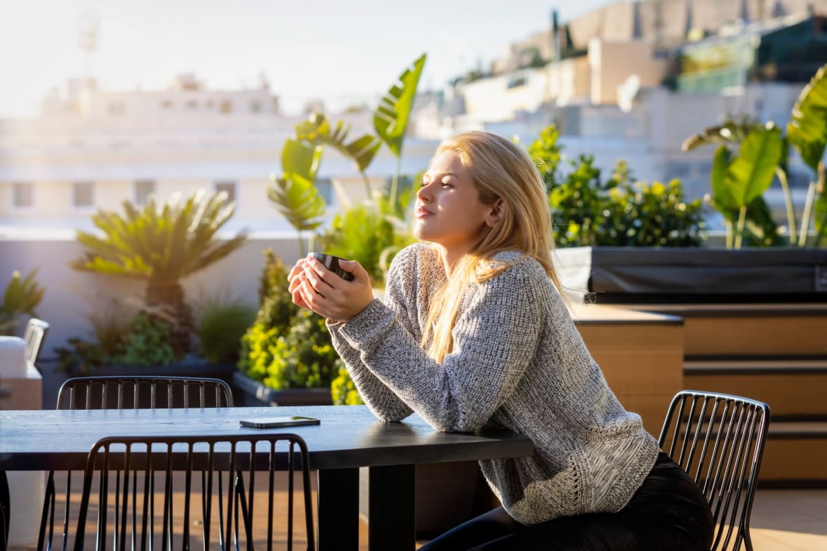 A resident enjoys a cup of coffee surrounded by the beautiful landscaping at Playa Marina, Los Angeles, California