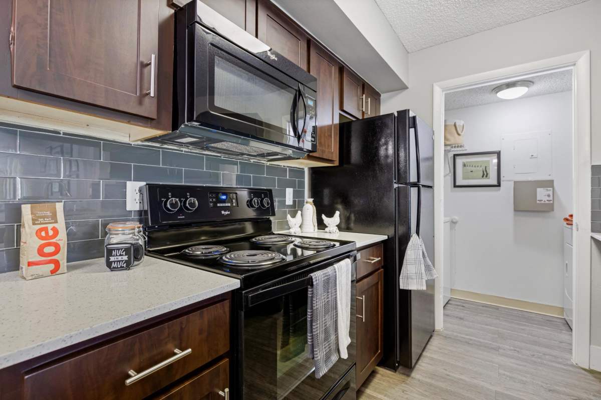 Kitchen equipped with black appliances at Centro at Davie Apartments, Davie, Florida