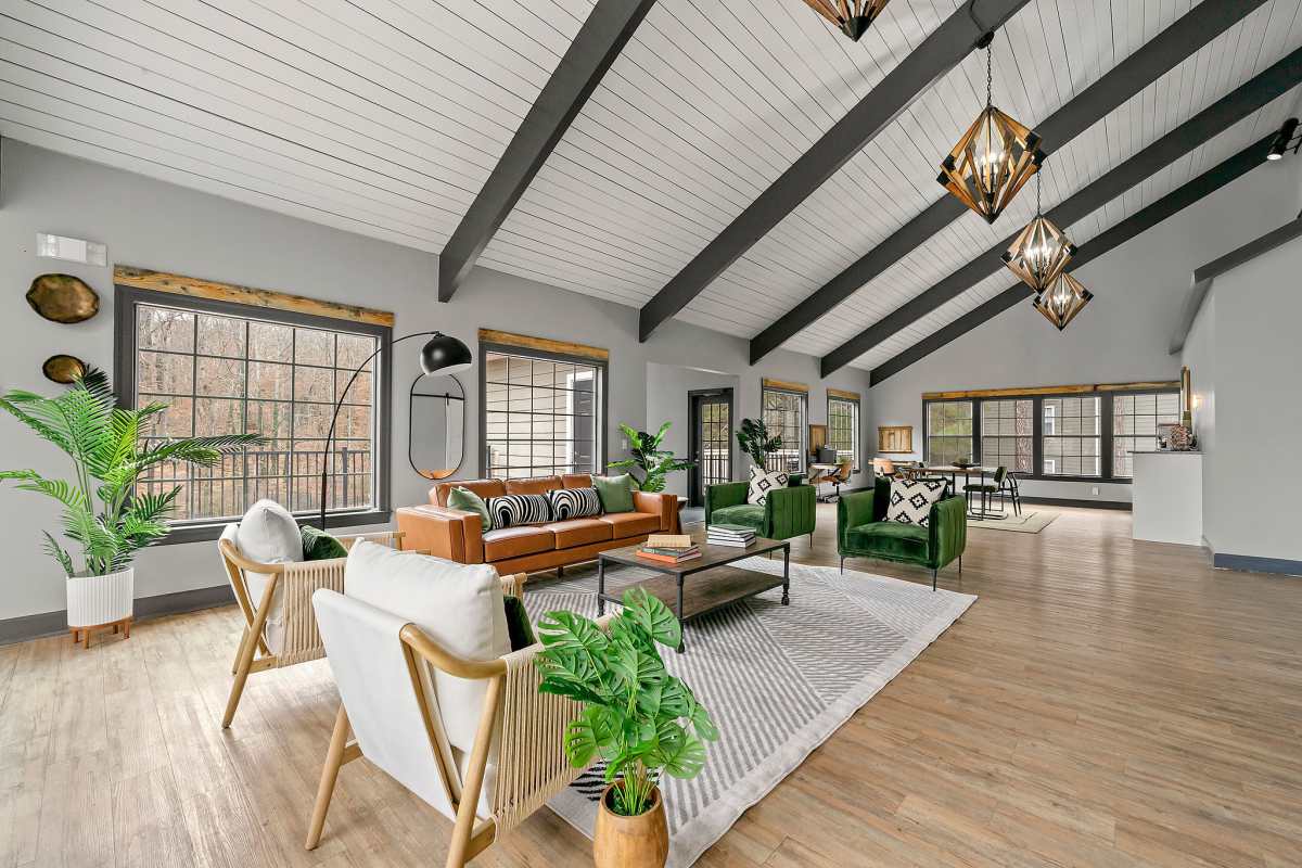 Community clubhouse with couch, chairs, pendent light and wood-style flooring at Fields at Peachtree Corners in Norcross, Georgia