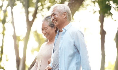 Two residents walking outdoors while linking arms at Canyon Creek Memory Care in Temple, Texas