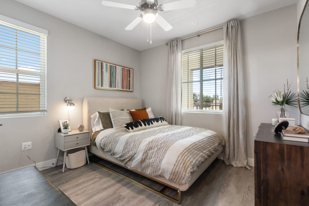 A furnished bedroom with wood-style flooring and a ceiling fan at Alivia Townhomes in Whittier, California