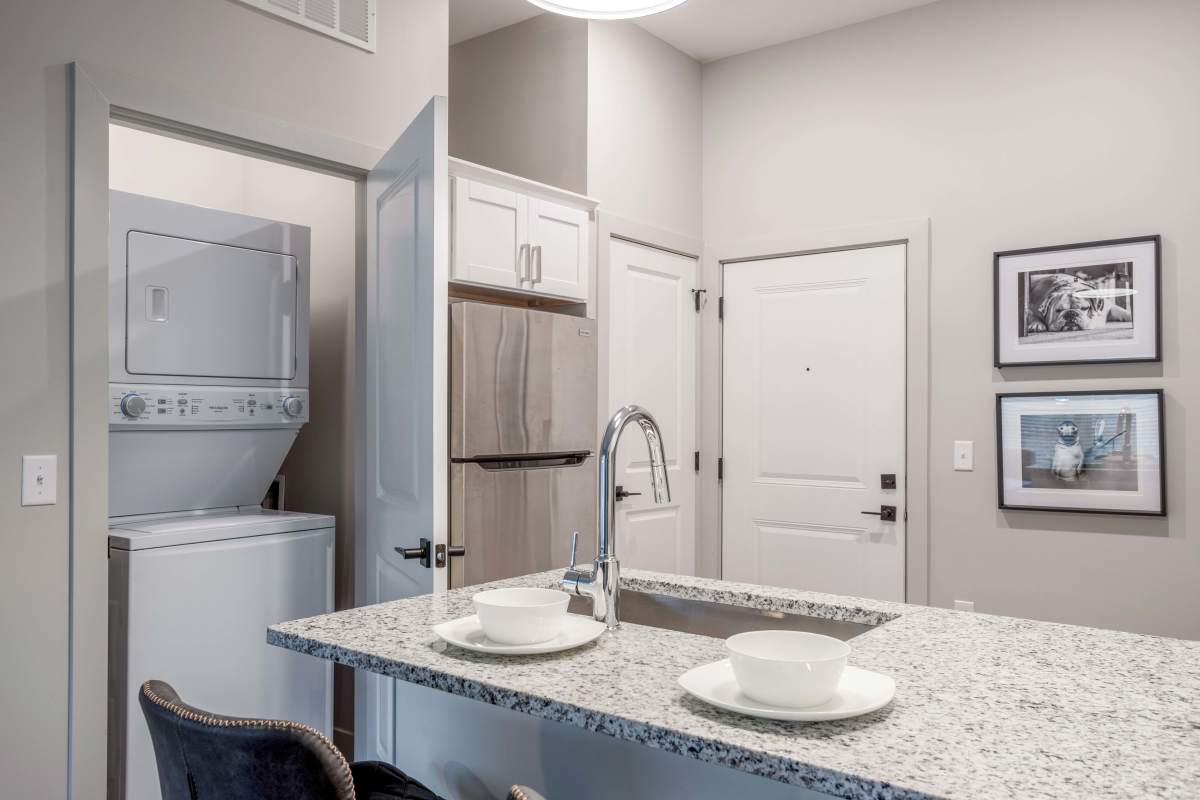 Kitchen with granite countertop and view of laundry room at Gateway Lofts in Lansing, Michigan