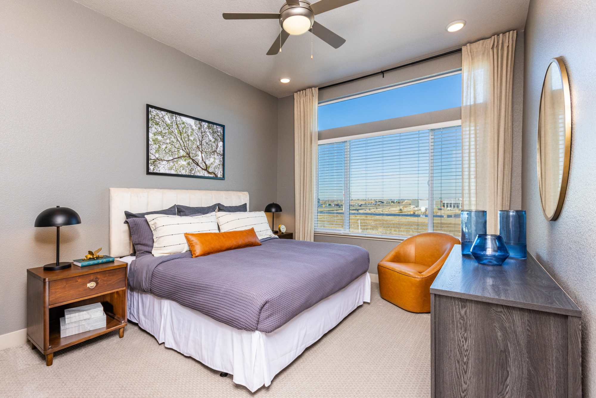Comfortable bedroom with king size bed, ceiling fan and large window at Zeta Luxury Apartments in Sacramento, California