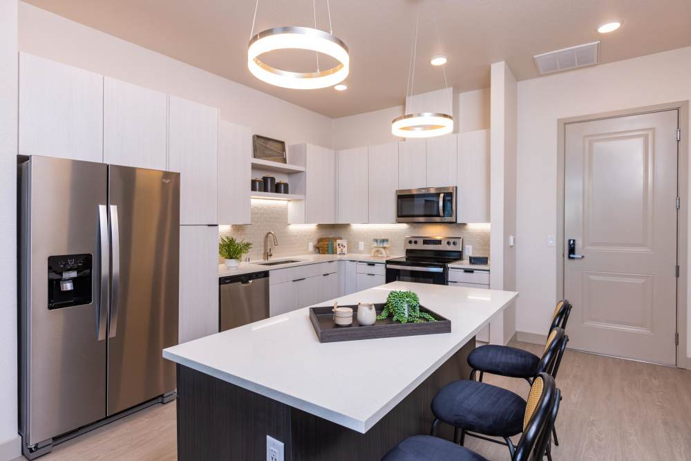 Modern kitchen with stainless-steel appliances and hanging lights at Zeta Luxury Apartments in Sacramento, California