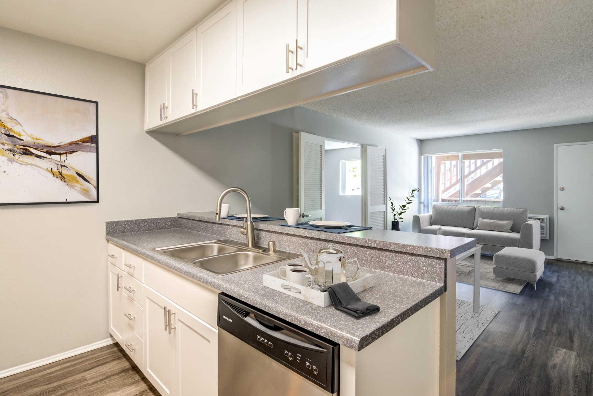 A renovated kitchen with white cabinets overlooking the living room at Hillside Terrace Apartments in Lemon Grove, California