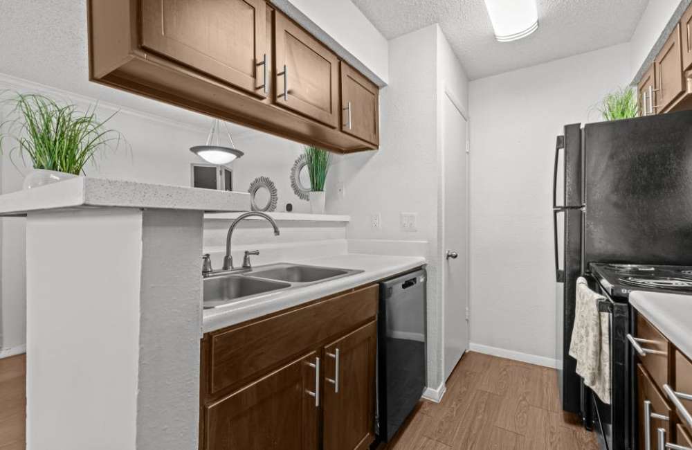 Modern kitchen with granite countertops, stainless steel appliances, and wood-style flooring at The Fielder in Austin, Texas