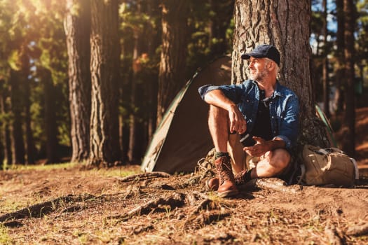 Man resting by a tree in the forest near The Alexander in Bend, Oregon