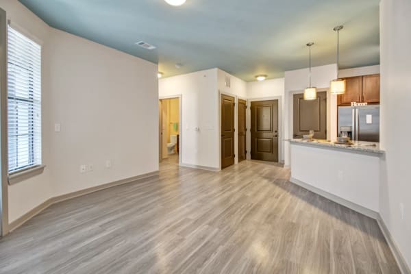 Living area and kitchen of an apartment home with wood-style floors at Duet in Nashville, Tennessee