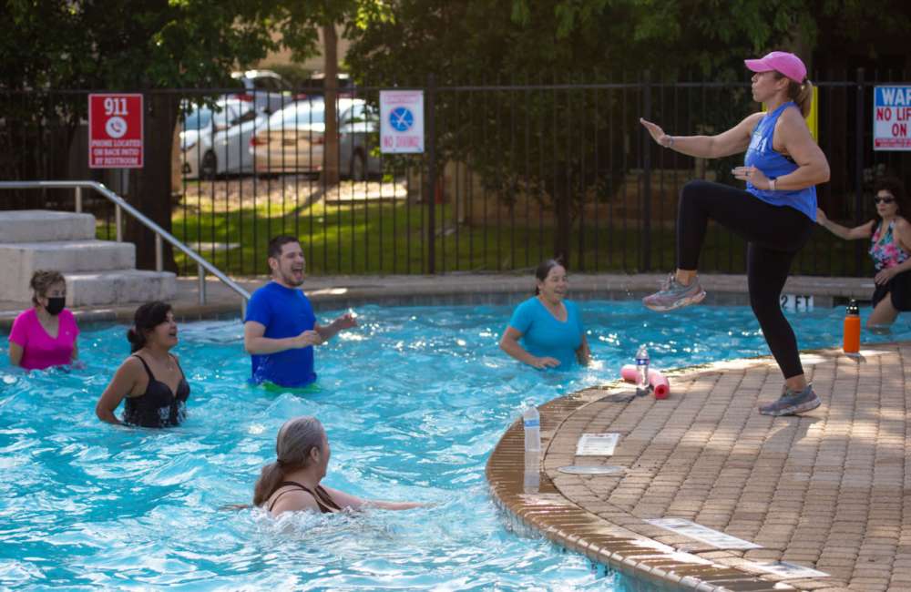 People swimming at Trails At The Park Apartments in Austin, Texas