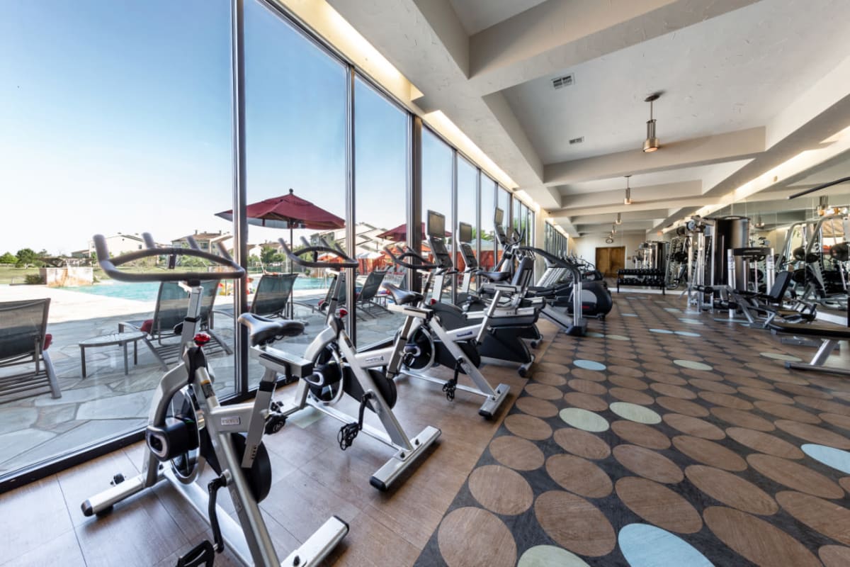 Cardio machines facing large windows with view of pool deck at Marquis at the Reserve in Katy, Texas
