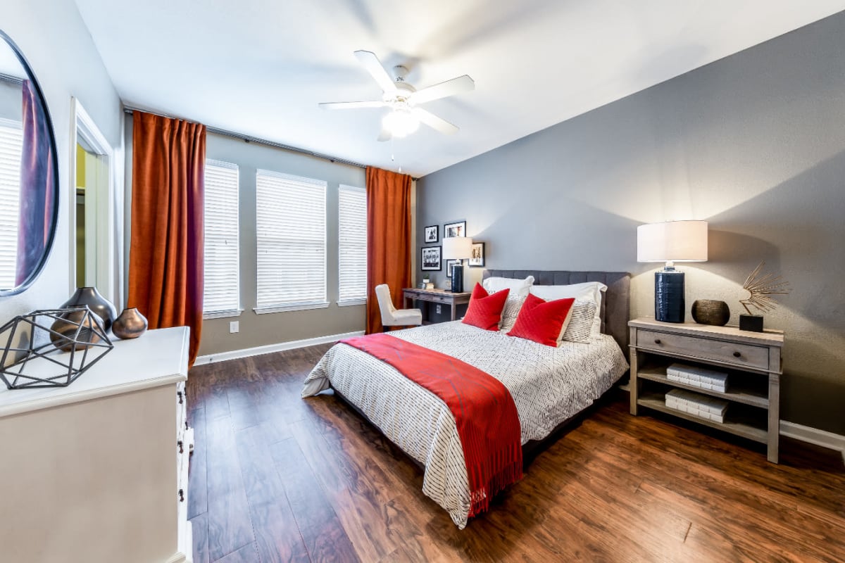 Bright and cheerful bedroom with wood flooring, multiple windows, and walk-in closet at Marquis at Stone Oak in San Antonio, Texas