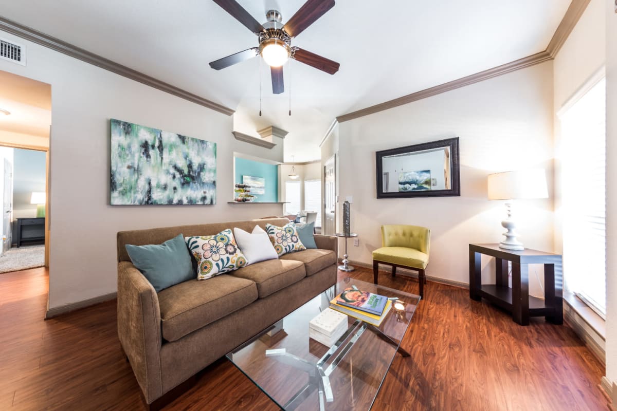 Bright and cheerful living room with wood flooring and ceiling fan at Marquis on Park Row in Houston, Texas