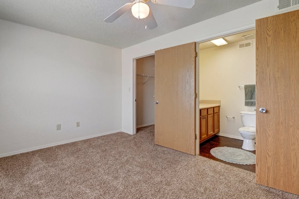 Bedroom with ceiling fan and attached bathroom at Yukon on 15th in Yukon, Oklahoma