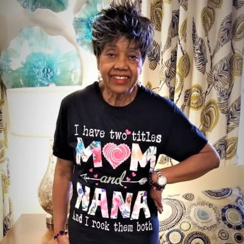 A resident wearing a party wig and posing for a photo at Ashbrook Village in Duncan, Oklahoma