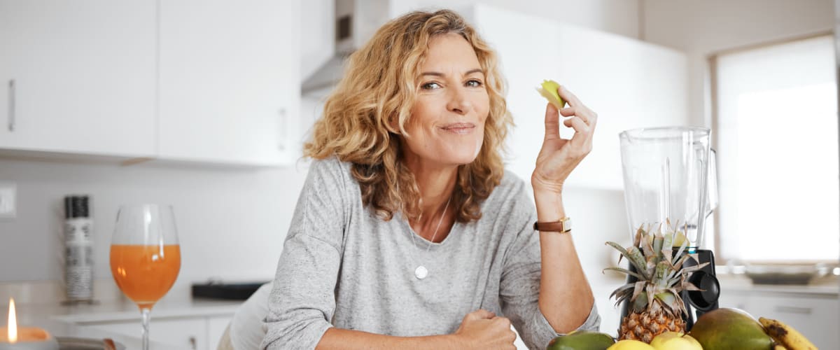 Resident eating an apple in her gourmet kitchen at Solaire 10914 Georgia in Silver Spring, Maryland